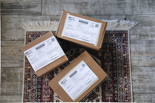 Three sealed cardboard boxes with shipping labels attached sitting on a patterned floor rug, ready for order fulfillment after discovering winning products on EPROLO.