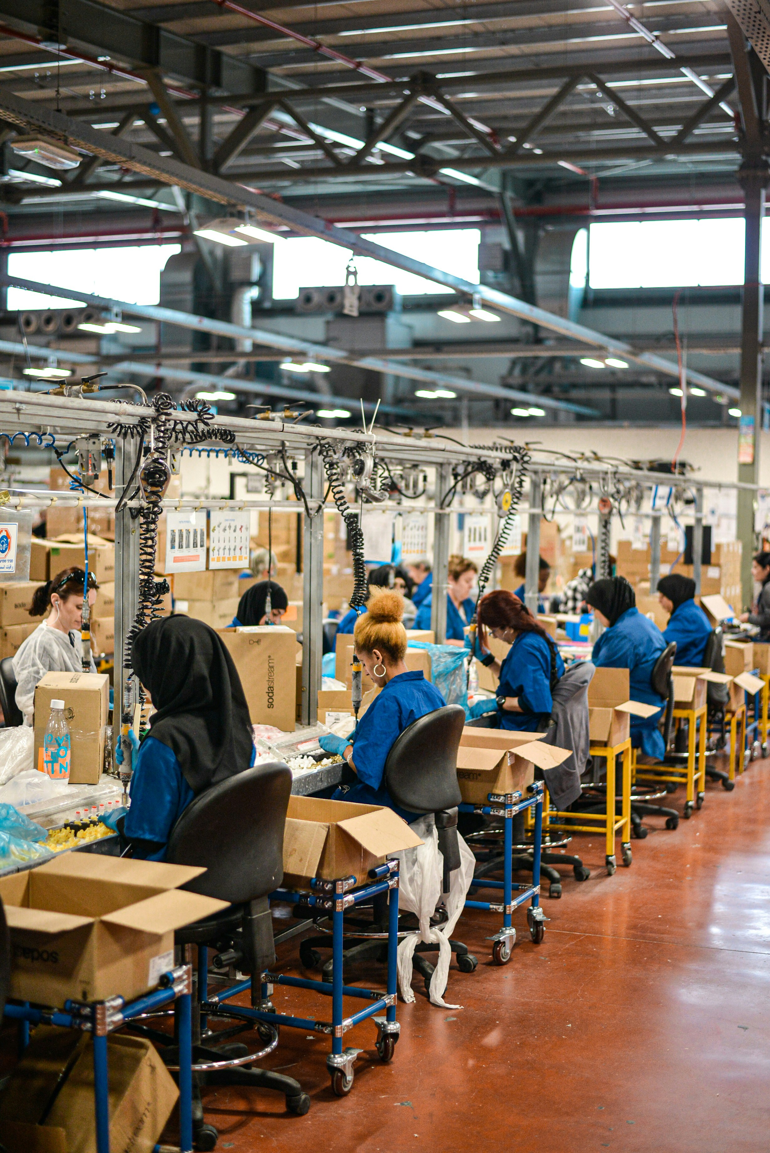 Factory workers efficiently packing items into cardboard boxes along an organized assembly line, representing seamless order fulfillment for EPROLO Fashion dropshipping inventory management.