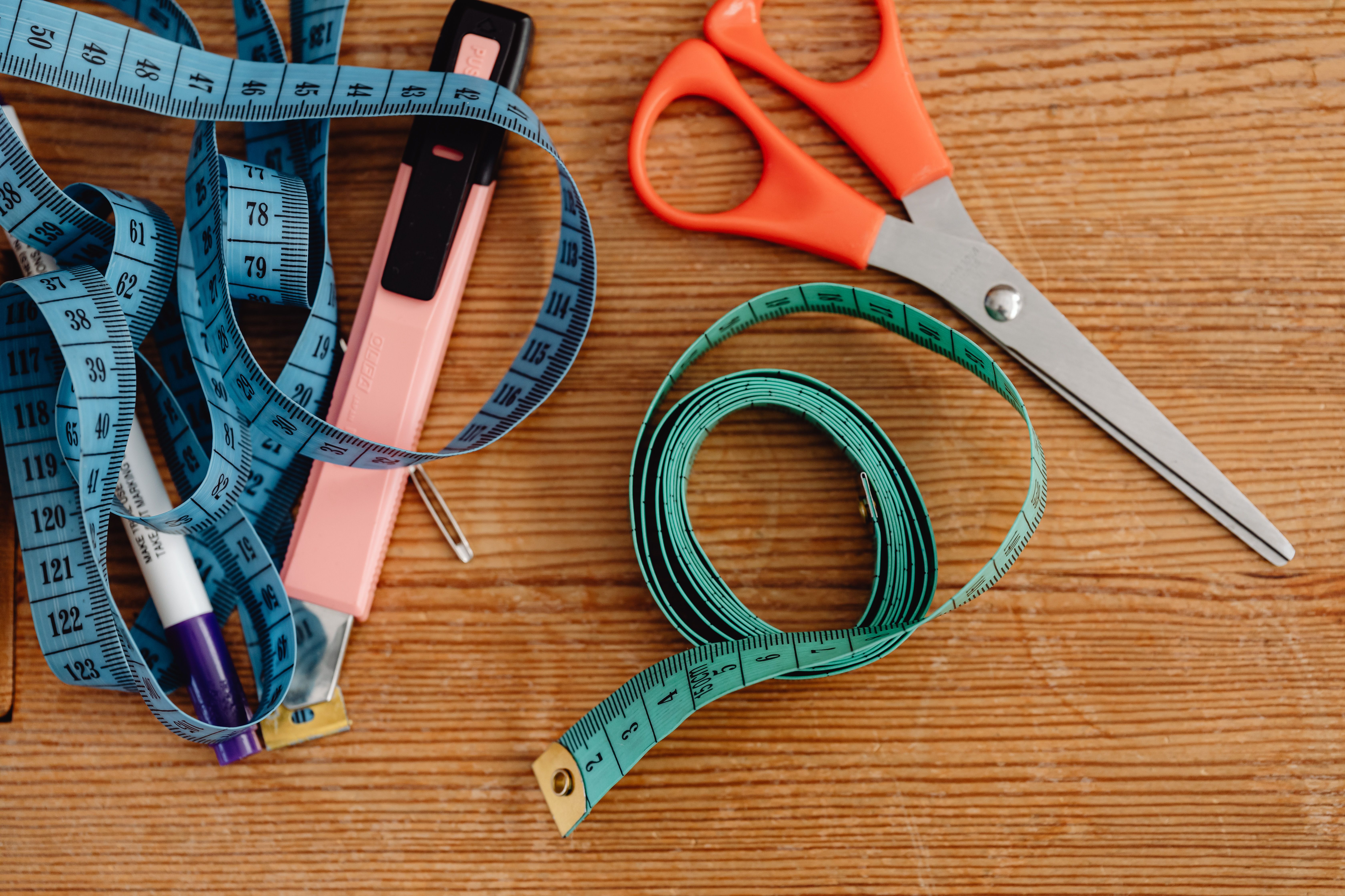 Tailoring tools used to solve fashion sizing disparities, curated by EPROLO on a wooden table.
