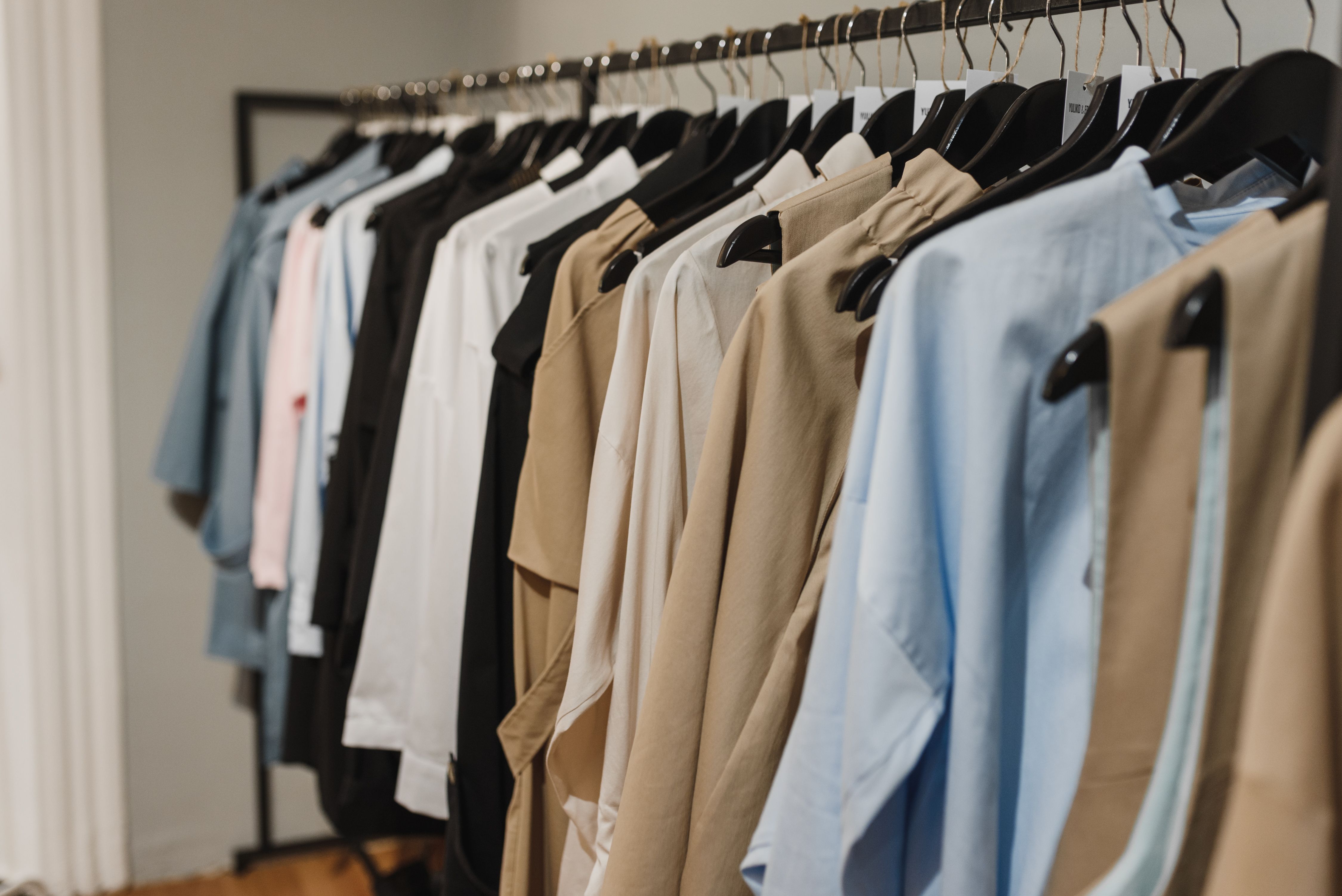 Premium wholesale apparel hanging neatly on a garment rack in a modern fashion showroom managed by EPROLO.