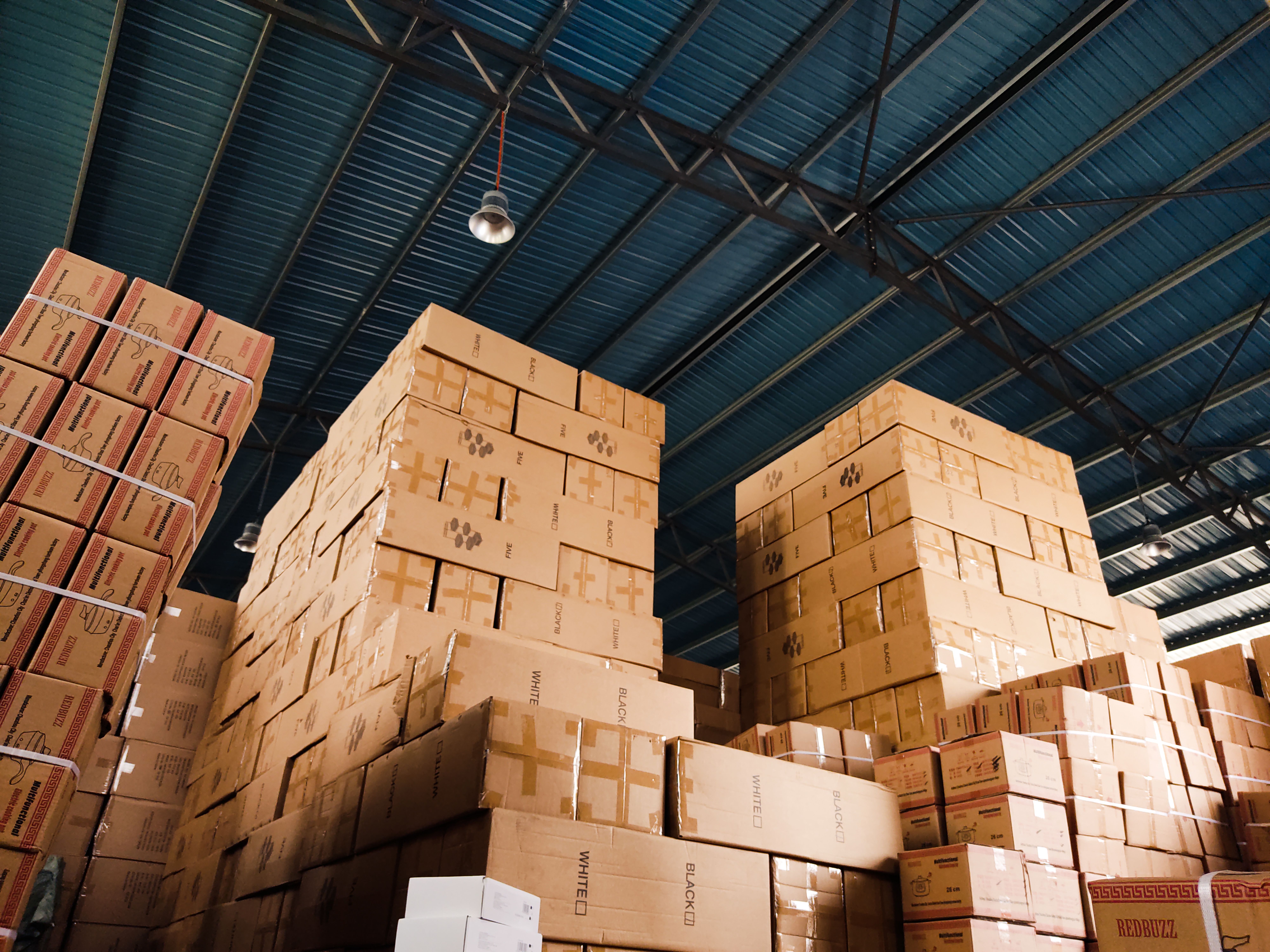 Stacking cargo boxes for supply chain fulfillment by EPROLO inside a massive distribution warehouse.
