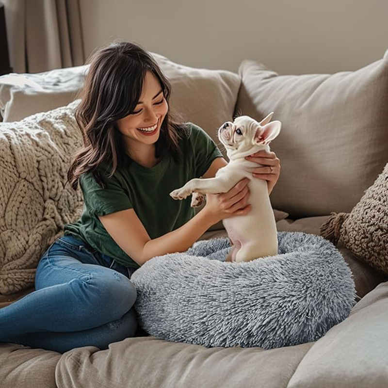 A smiling woman playing with her puppy on a plush bed, featuring the best pet products to sell online from EPROLO.