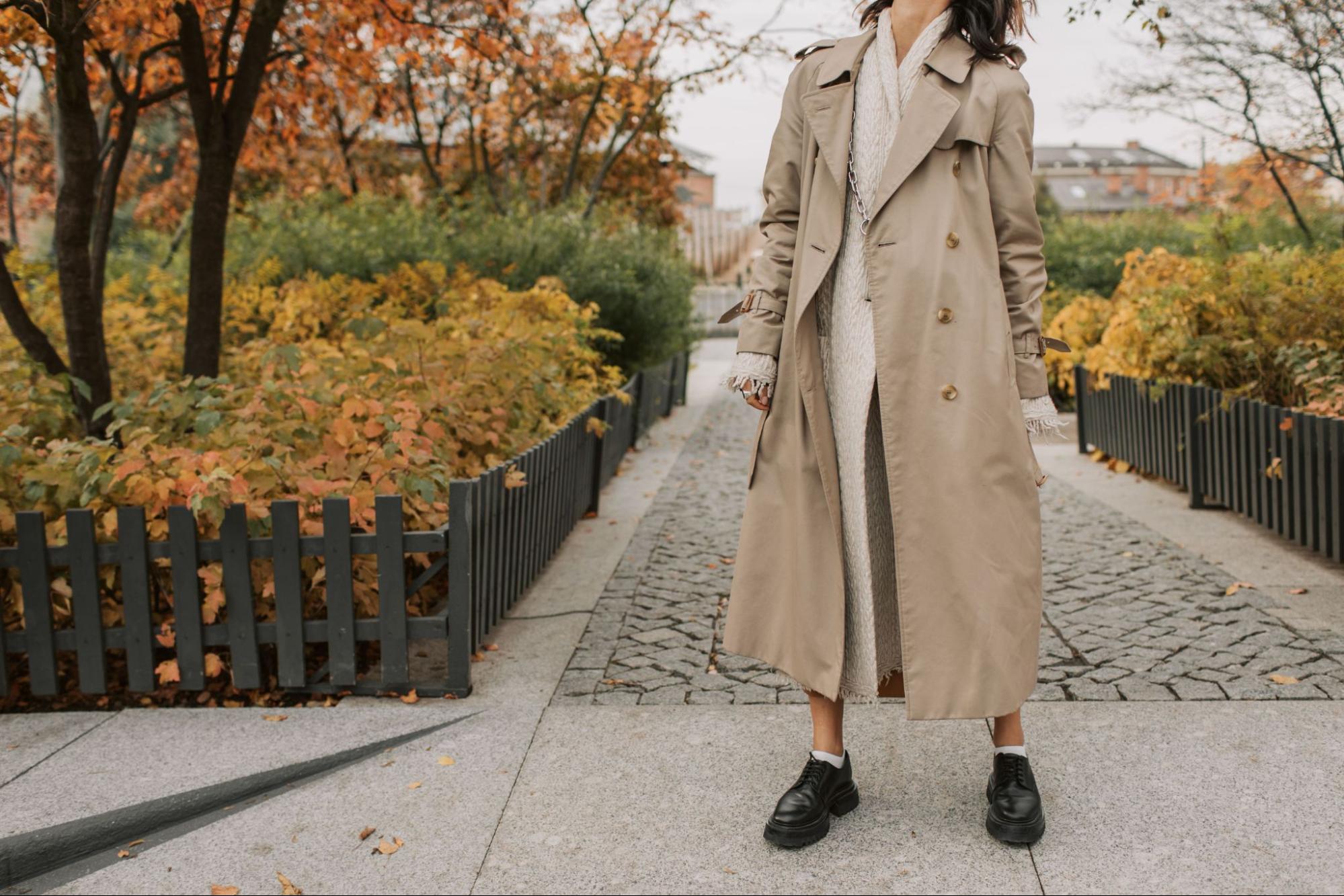 A woman wearing a trench coat showcases fall fashion trends for dropshipping products.