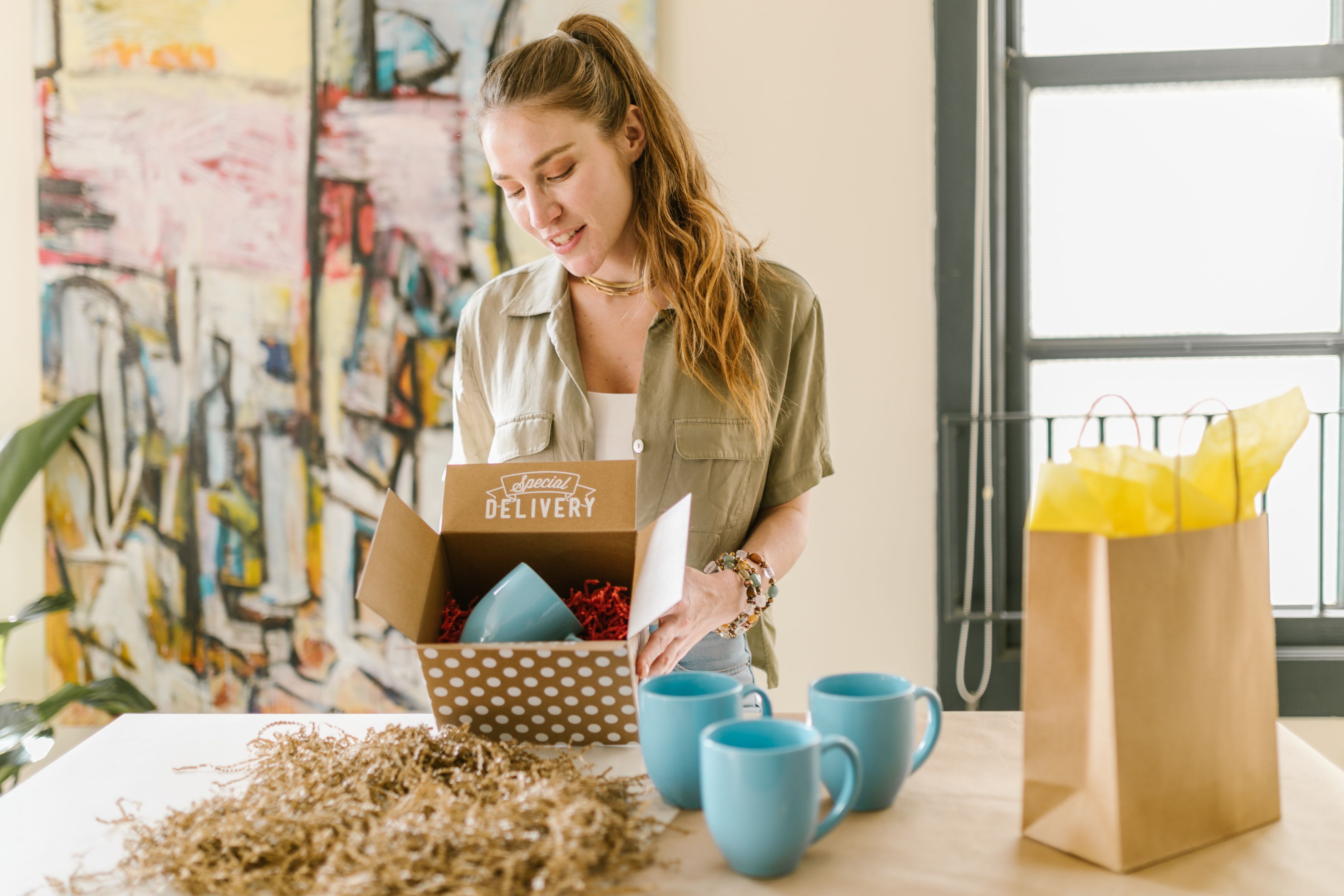 A woman pursues profitable business ideas by packing ceramic mugs into a gift box.