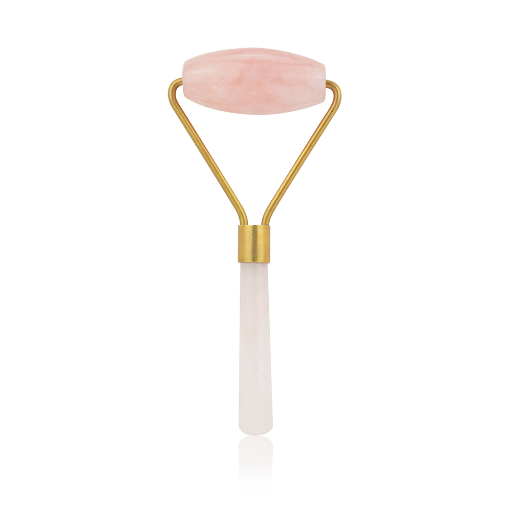 Flat rose quartz massage stone on cream wood handle with brass ferrule, used for gua sha techniques