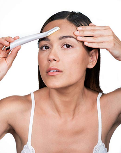 Woman guiding illuminated tool across forehead