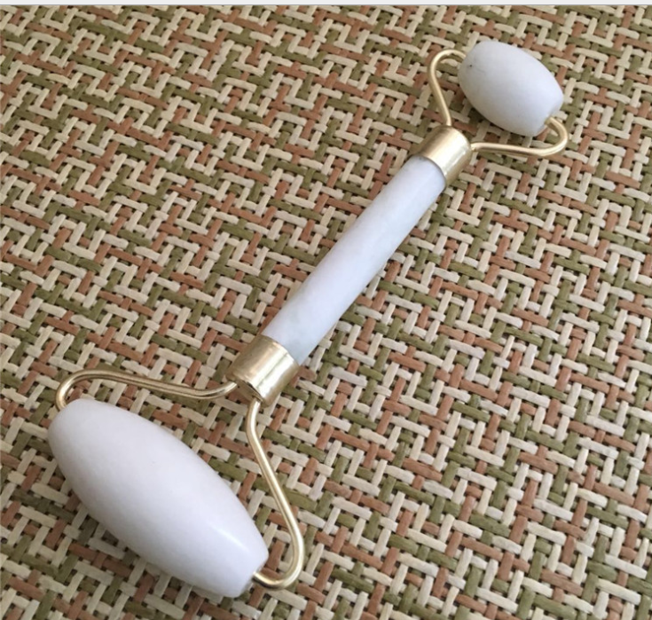White jade roller displayed on woven natural fabric surface
