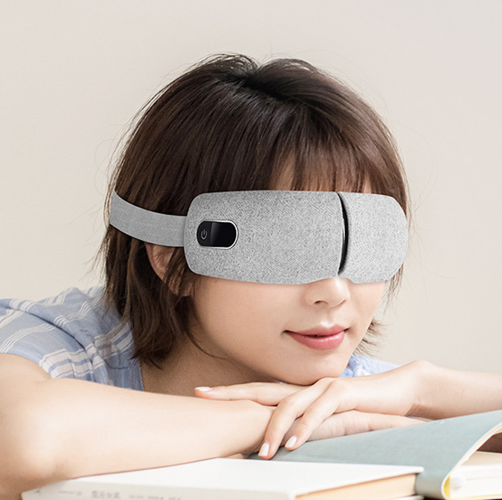 Woman squinting at bright laptop screen, eye massager positioned nearby