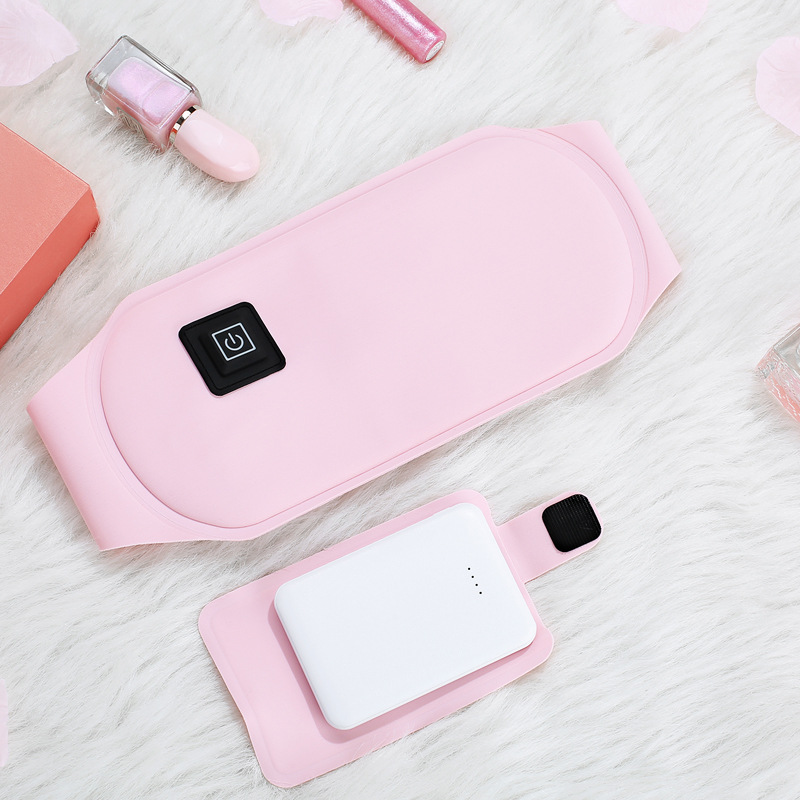 Pink graphene heating belt with power button and USB cable, flat lay on ivory surface