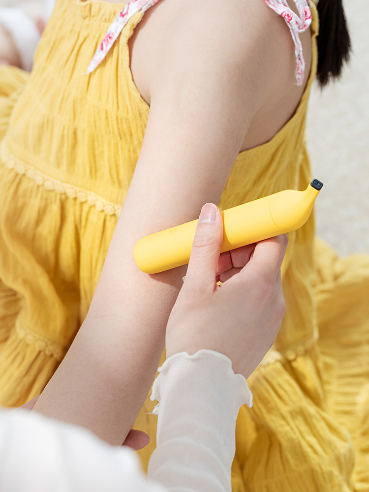 Child in yellow dress applying the banana anti-itch pen to arm, demonstrating safe and easy family use