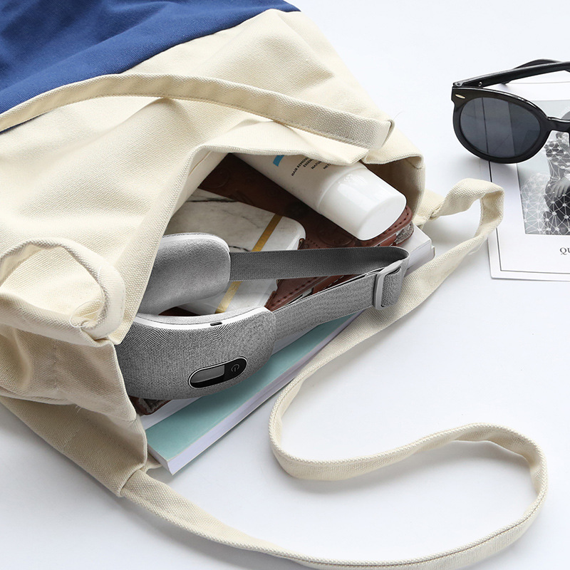 Open cream canvas carrying case with eye massager, USB cable, and dried wildflowers