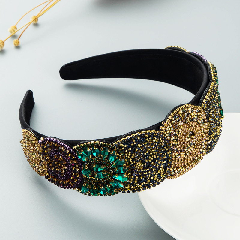 Gold and teal embellished headband arranged on pale surface