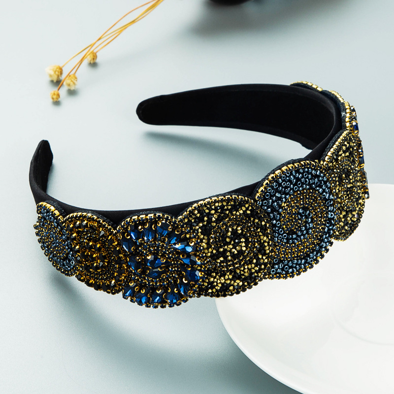 Dark embellished headband styled on pale tabletop