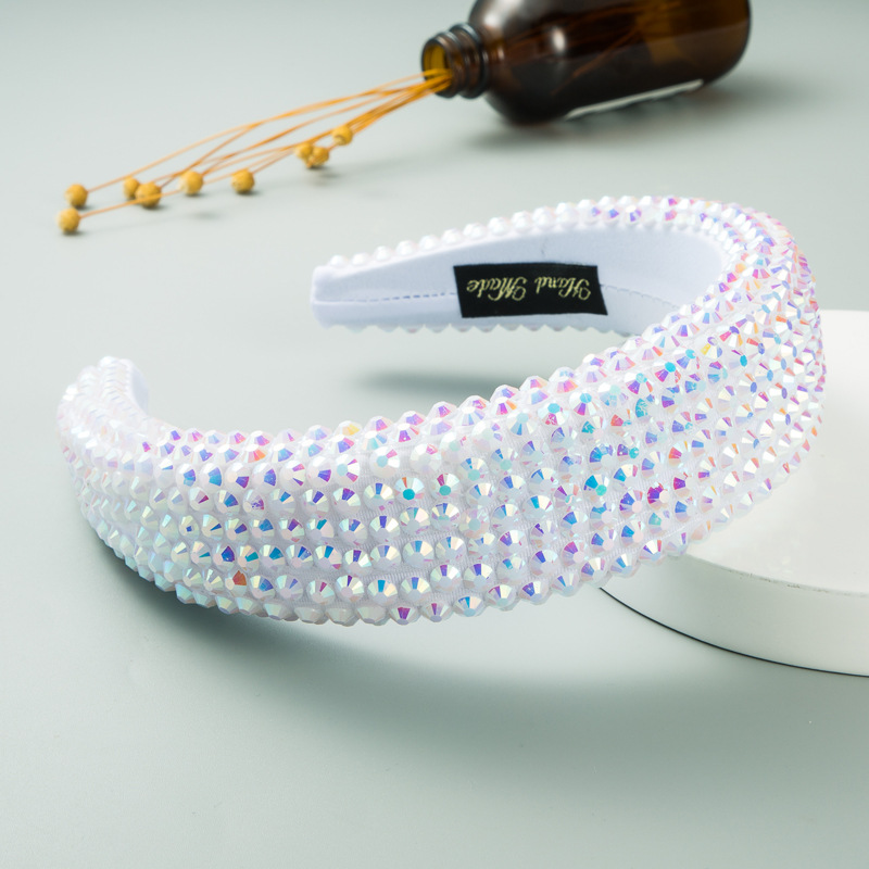 Iridescent white padded headband beside cosmetics