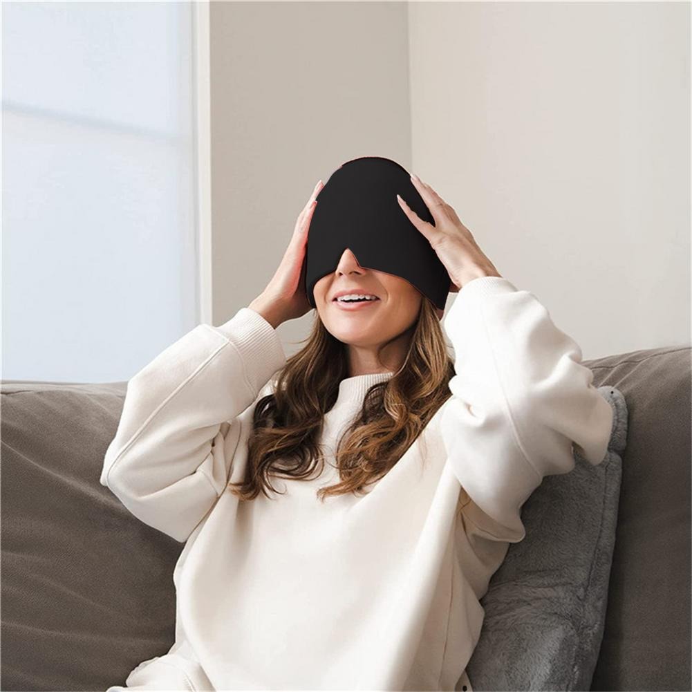 Woman relaxing on couch adjusting elastic strap of black headache relief mask, smiling contentedly in bright home setting