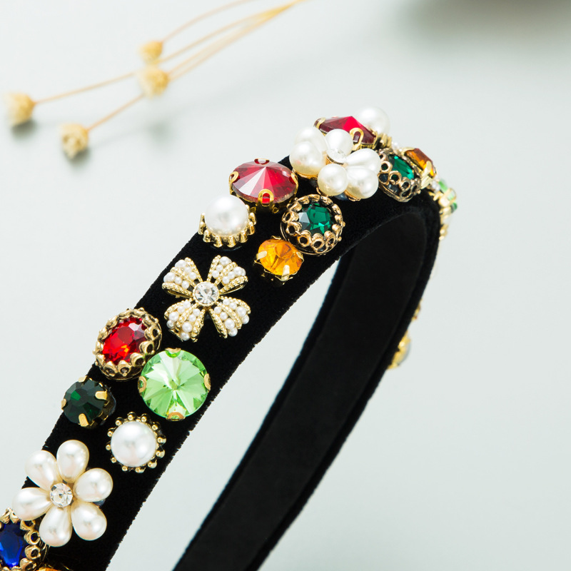 Close-up of pearl clusters, red green gems, gold filigree, and rhinestones