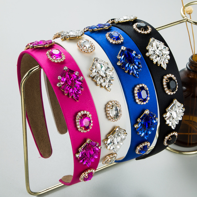Five colorful embellished headbands on gold display rack