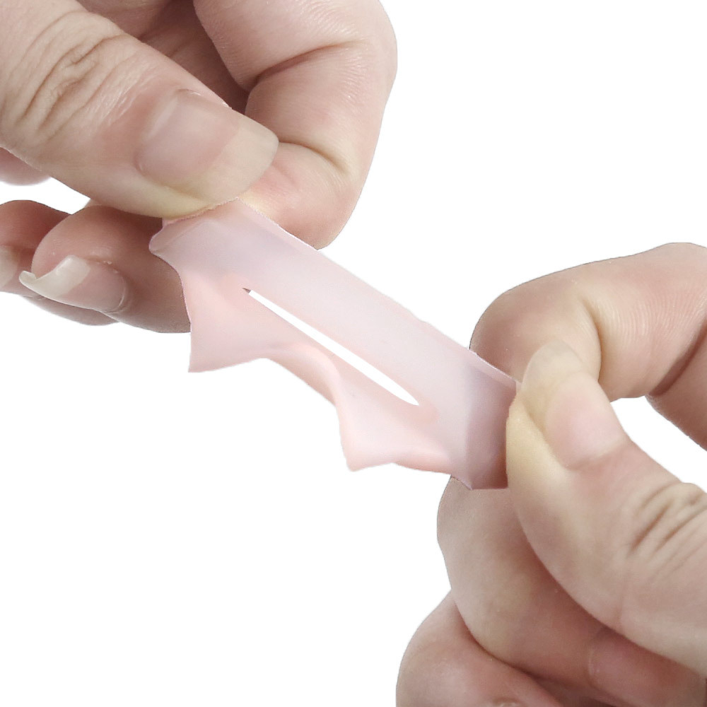 Hand squeezing the transparent silicone corrector to demonstrate its soft, medical-grade flexibility