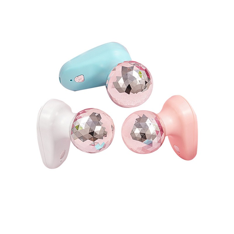 Three compact fascia guns in white, pink, and blue with interchangeable crystal massage heads on a soft pastel background