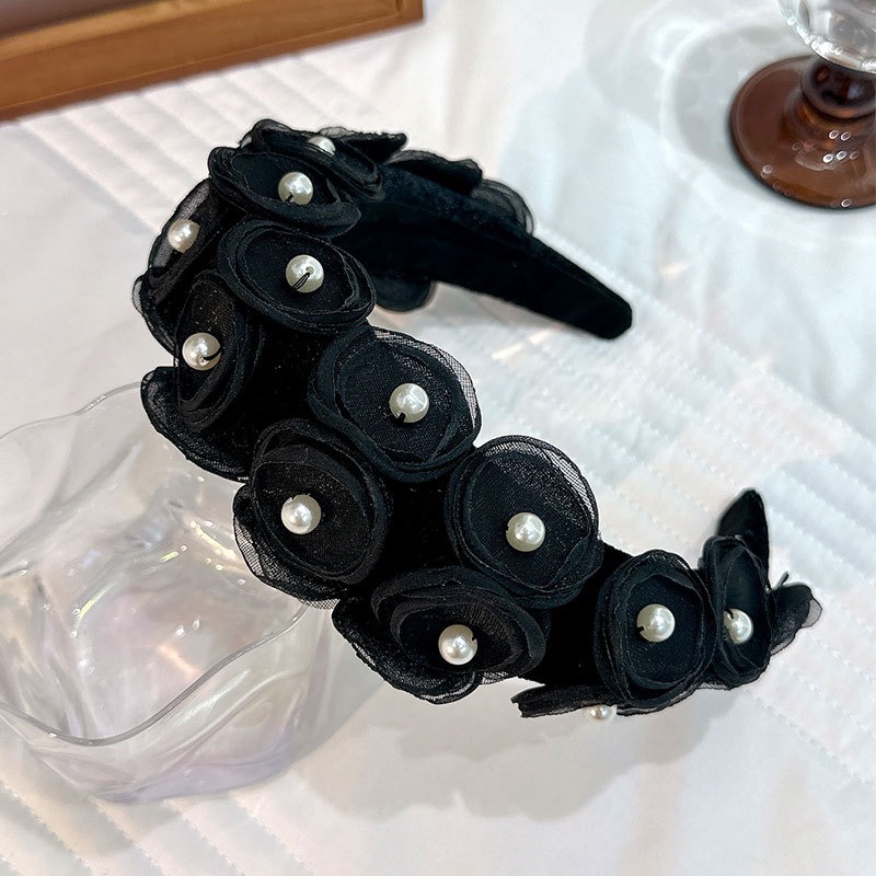 Structured black floral headband showing curved profile