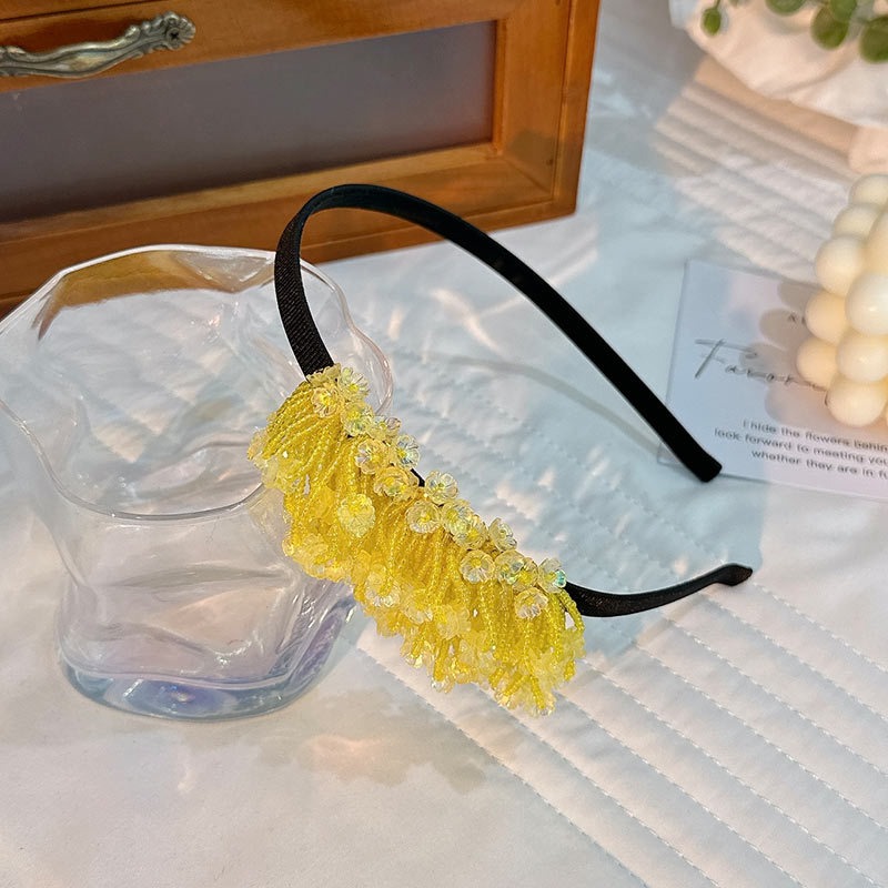 Layered yellow beaded flowers and tassels on black hoop
