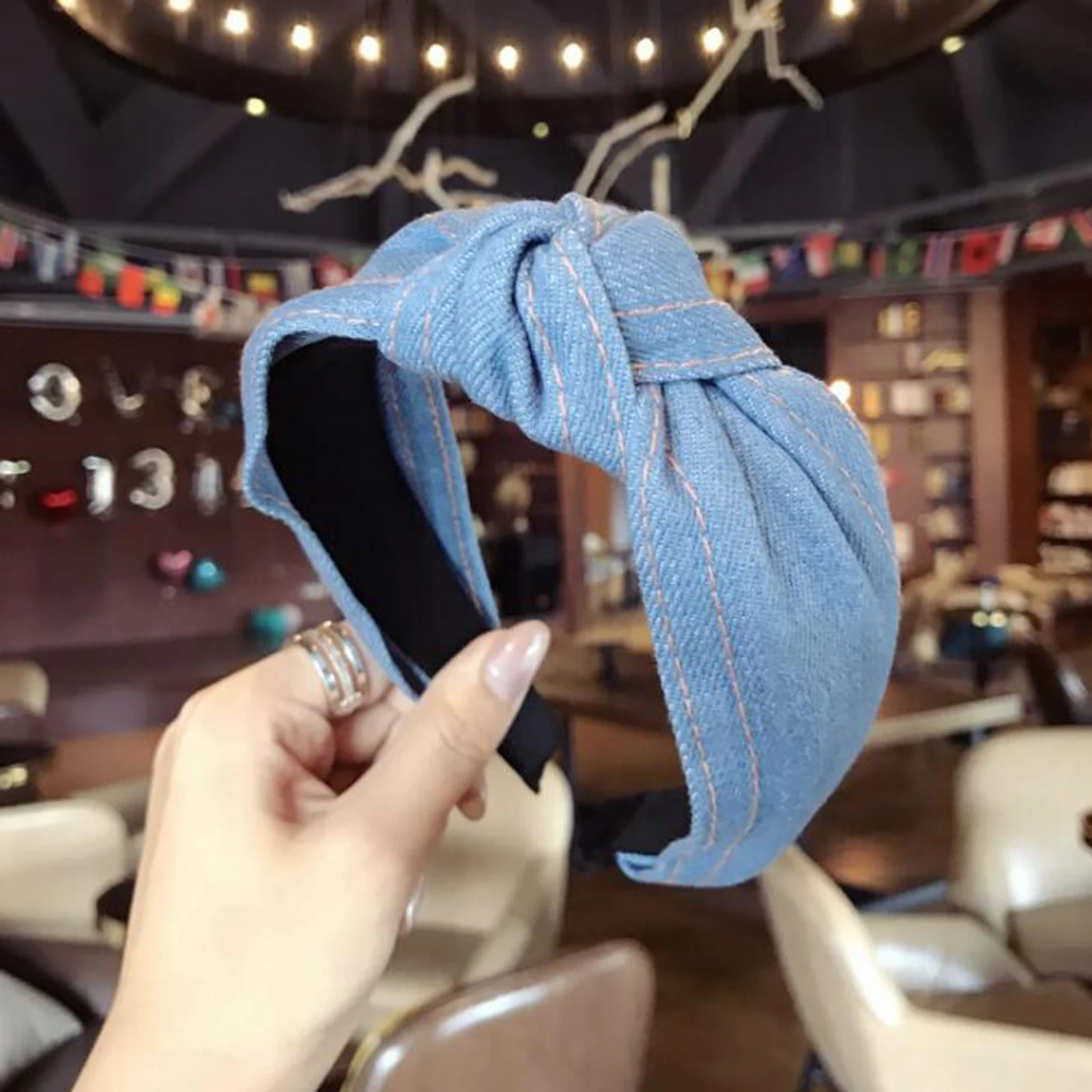 Denim headband held against a casual lifestyle backdrop