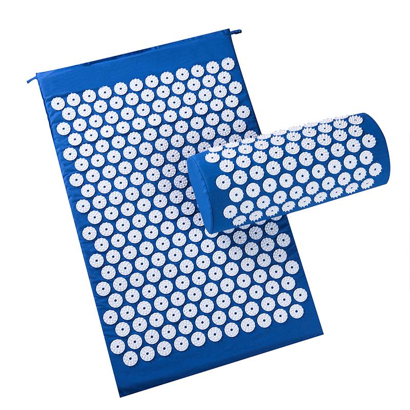 Blue acupressure mat with matching cylindrical pillow laid flat on a pale grey surface
