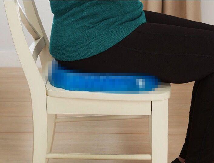 Egg Sitter cushion in use on wooden chair with person sitting, showing real-world application