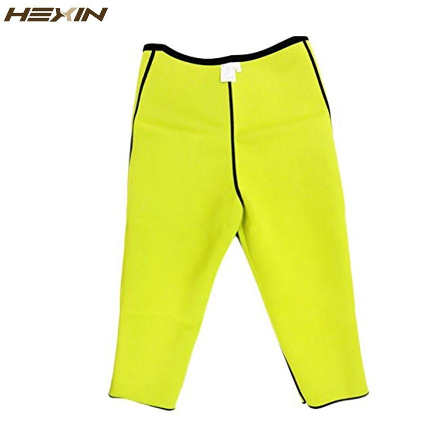 Full-length neon yellow neoprene slim pants with black waistband, flat lay on brushed champagne metal with rosemary sprig