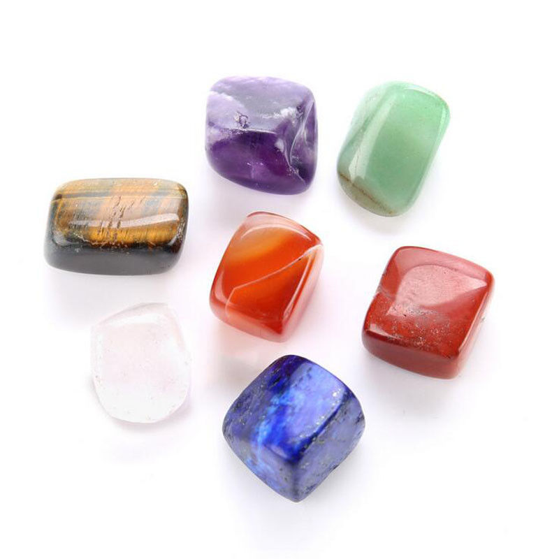 Seven polished tumbled chakra stones on a white background showing natural color and texture