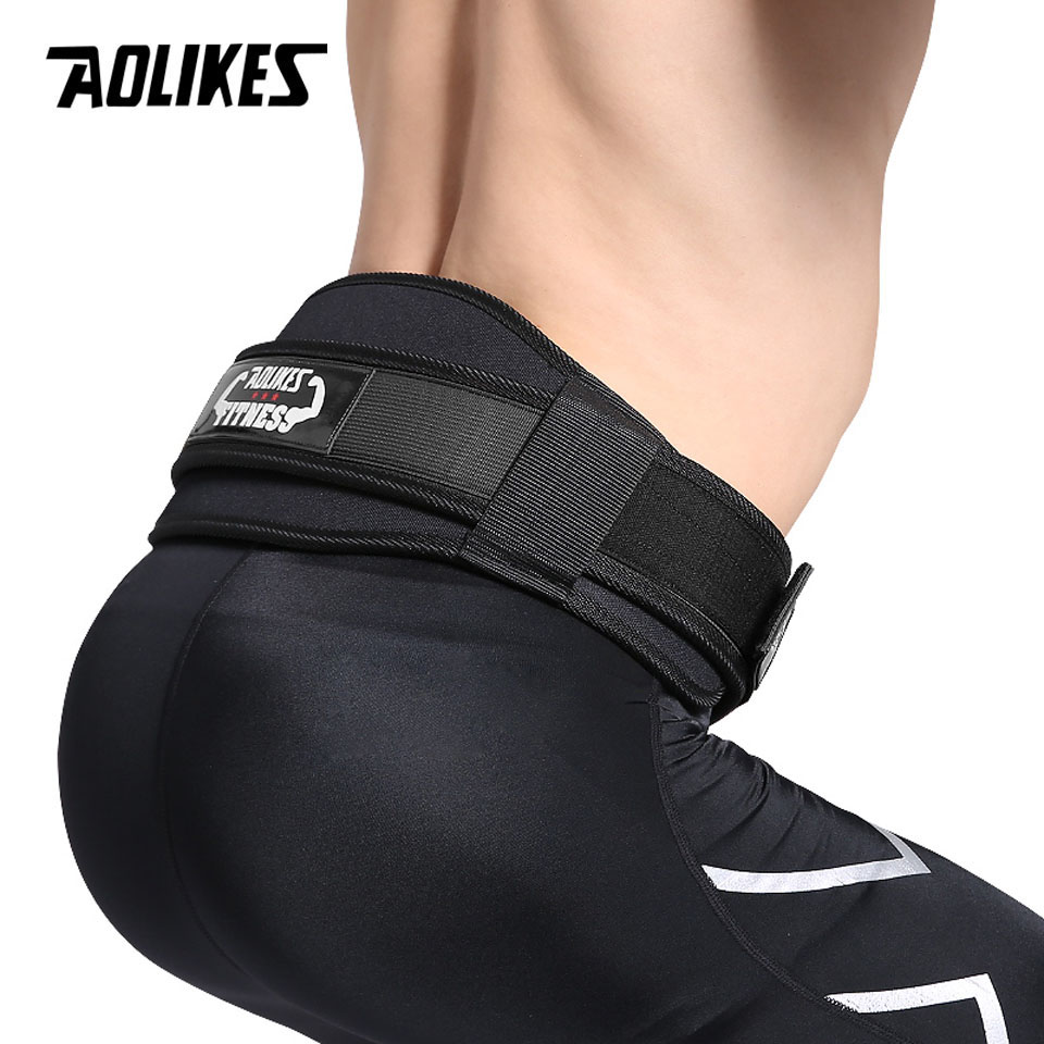 Black weightlifting belt worn by an athlete on a gym floor, hinting at lower back discomfort before using support
