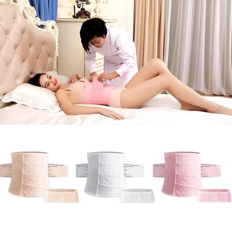 Woman receiving fitting assistance for postpartum corset belt, lying on bed post‑surgery