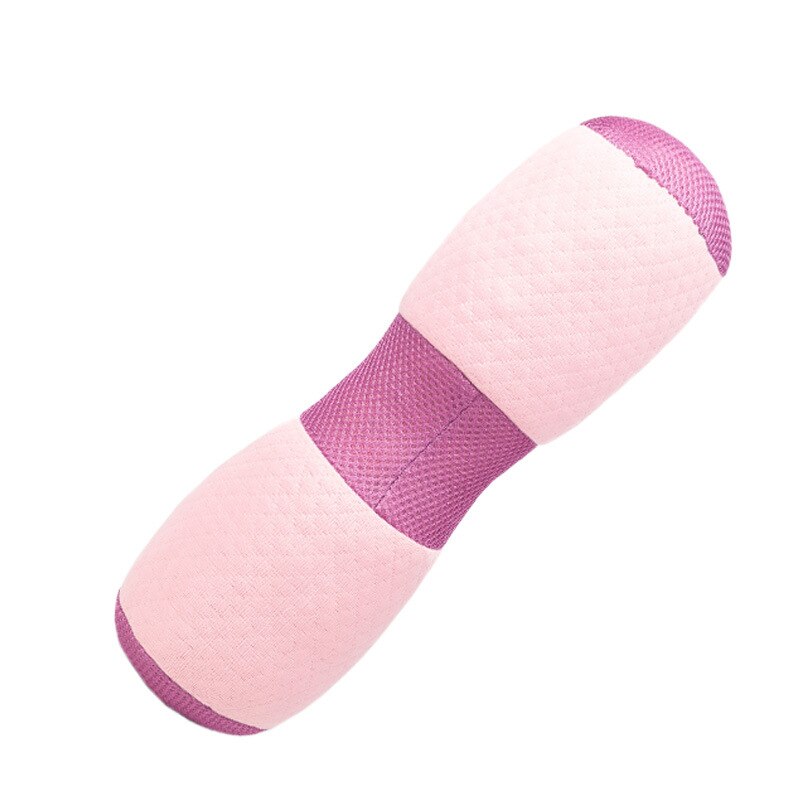Pink yoga bolster with color-blocked design and accompanying support roll, displayed on pale apricot suede surface