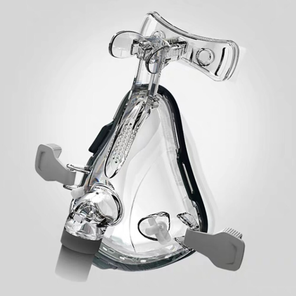 Full-face CPAP nasal mask with clear silicone cushion and adjustable black headgear on a soft celadon backdrop