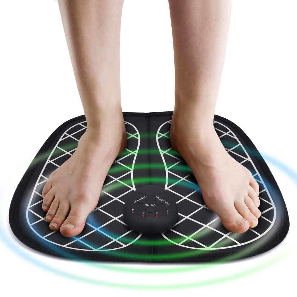 Feet resting on EMS foot massage mat, illuminated by green and blue LED acupressure indicators signaling active muscle stimulation