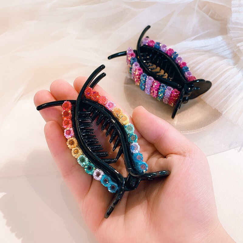 Hand holding open clip with curved claw teeth