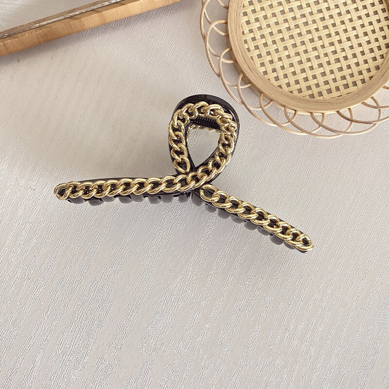 Black claw clip showing raised gold chain texture