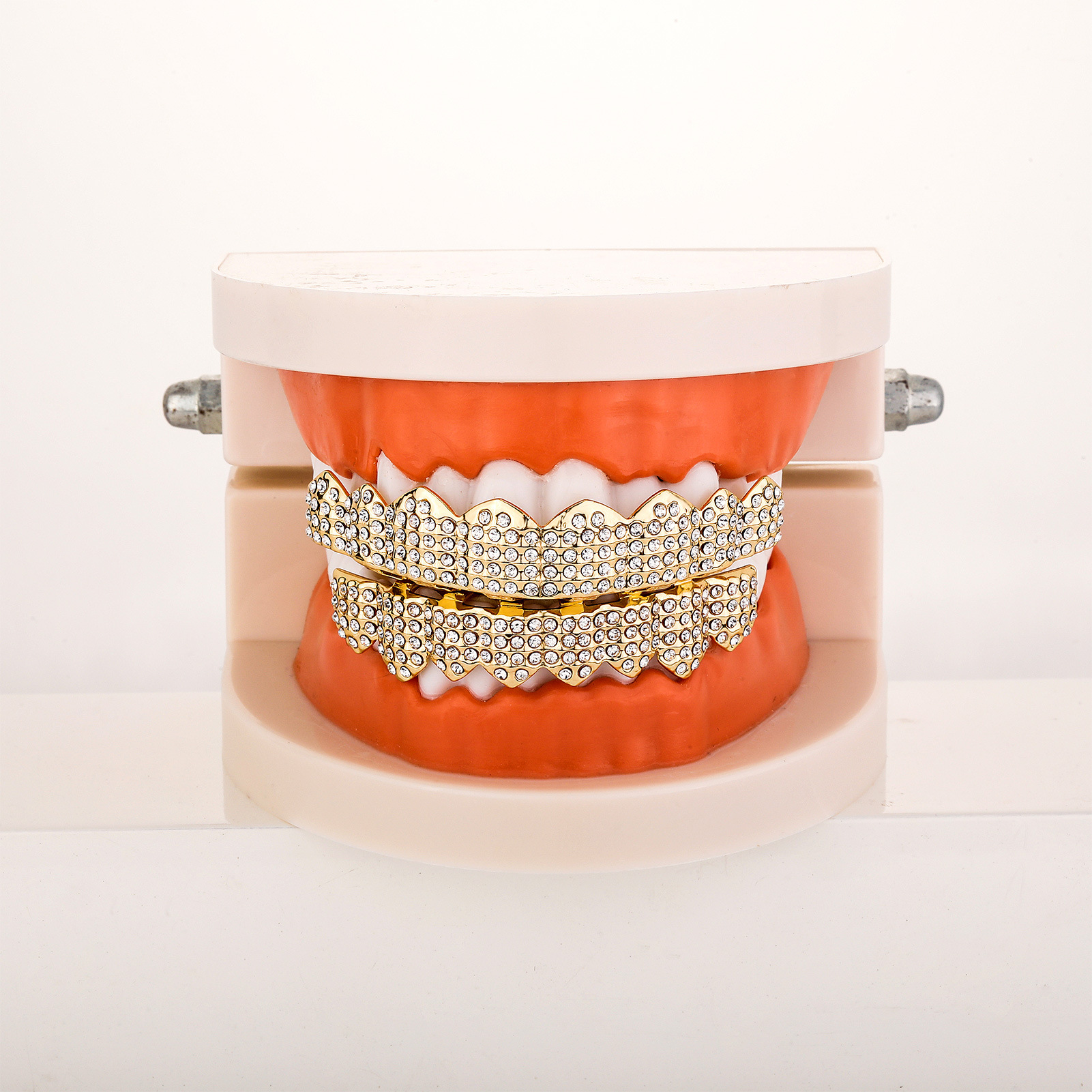 Gold rhinestone grillz fitted on a dental jaw model demonstrating the full, dramatic iced-out smile