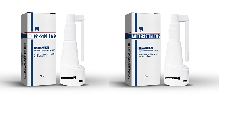 Clinical white spray bottle with navy blue band and tooth logo, displayed on light birch plywood with dried palm fronds in warm golden-hour light