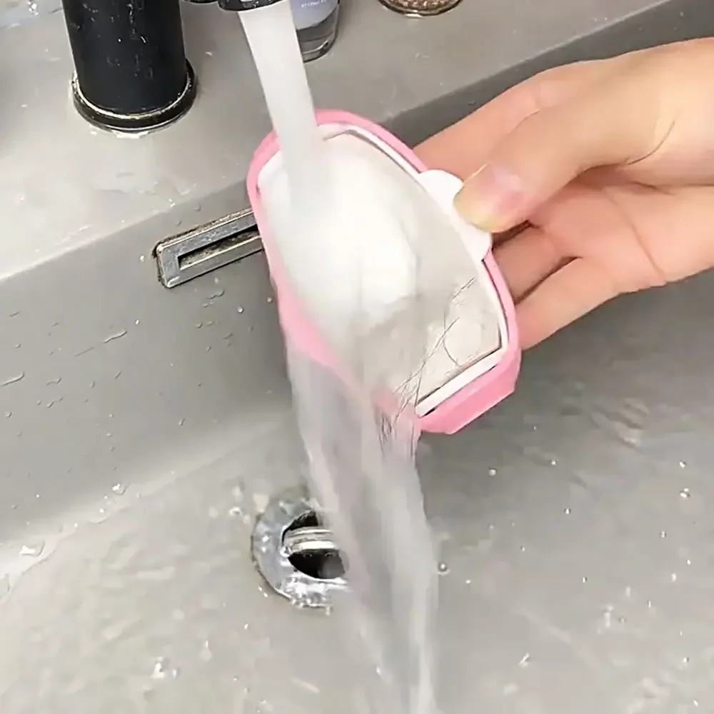 A pink penguin lint roller being rinsed under running water at a bathroom sink, with fur washing off