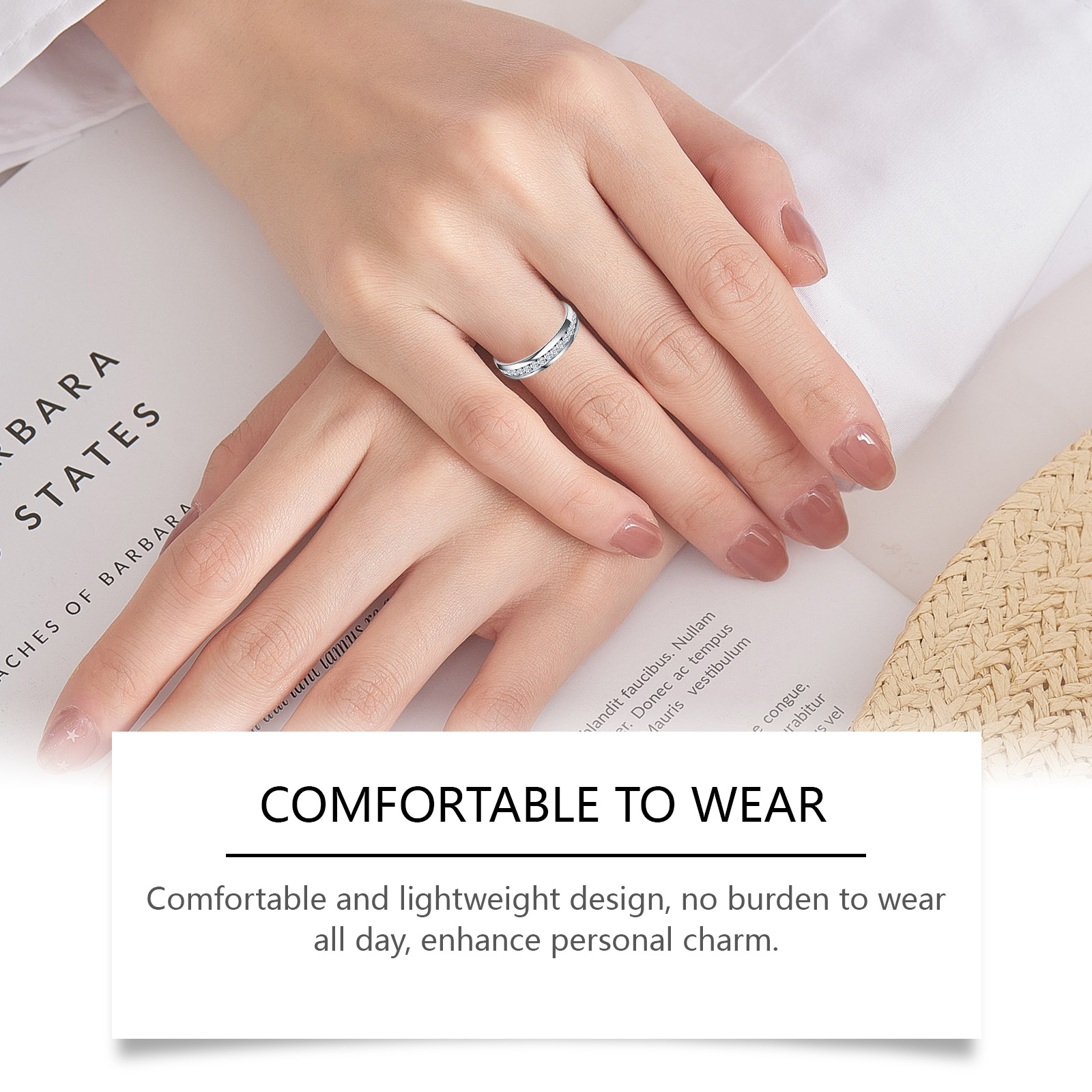 Silver ring worn on hand beside open book