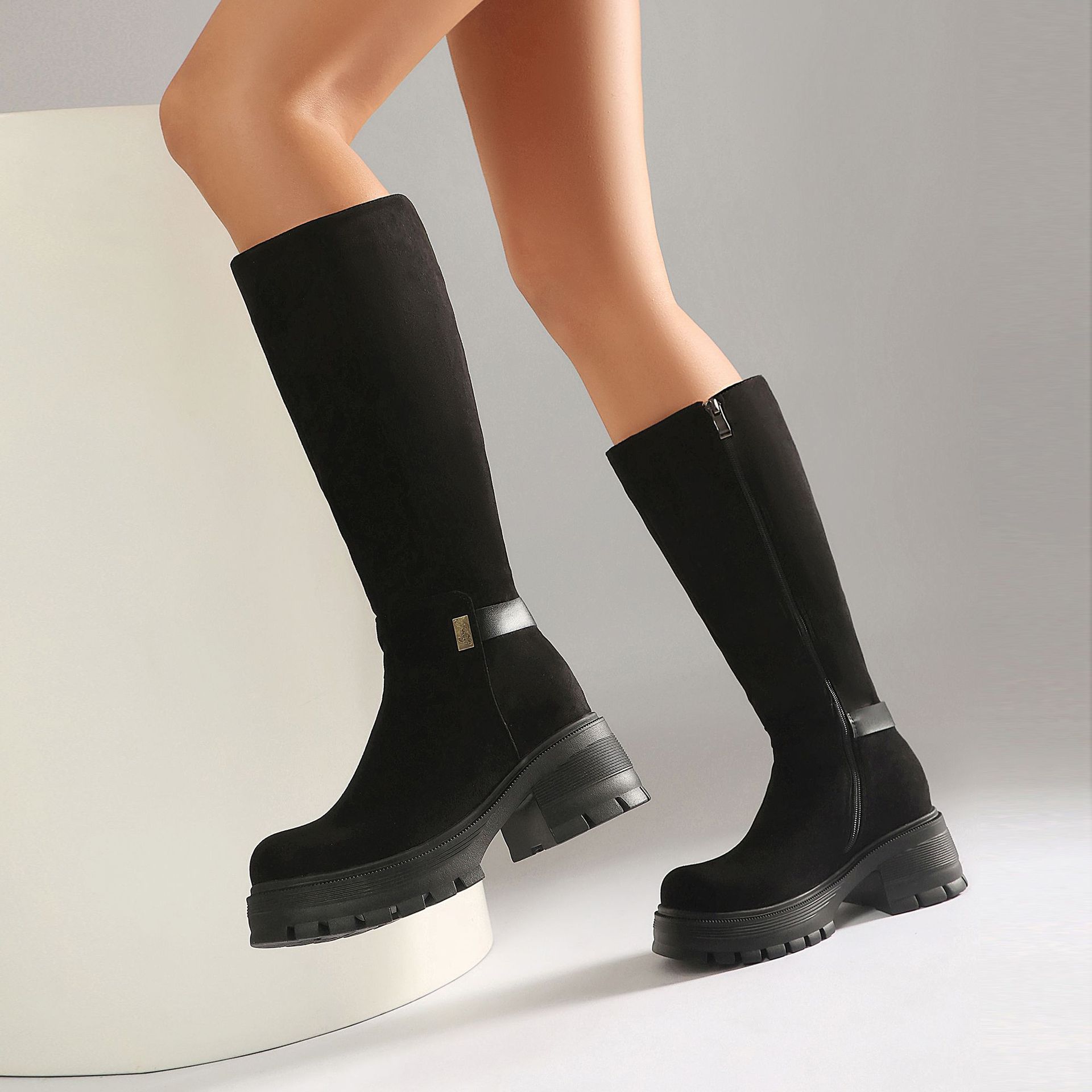 Black faux suede knee-high boots – front view on model showing full boot and outfit styling
